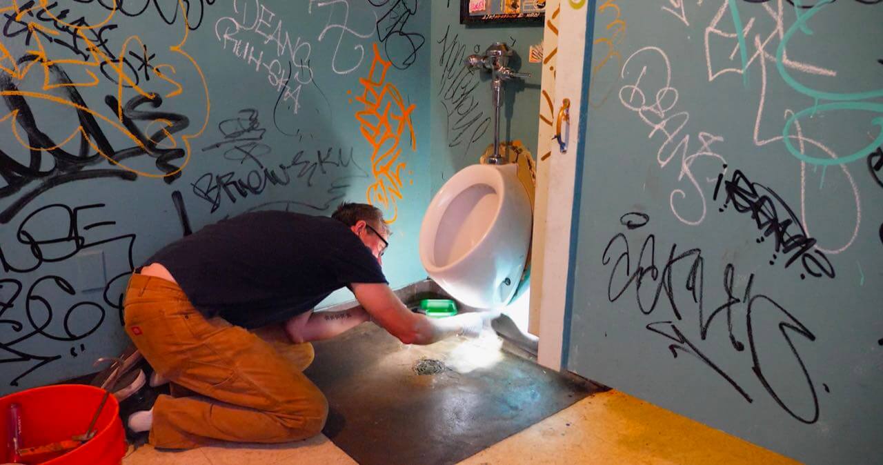 Dan Ayala working on punk club toilet, screen grab from the film